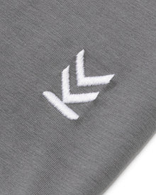 Detail shot of embroidered logo at bottom left hem of Stone Grey Wild Tee