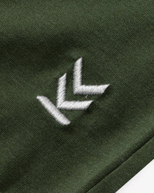 Detail shot of embroidered logo at bottom left hem of Forest Green Wild Tee