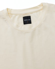 Close-up of branded neck tag and soft collar opening on cream modal cotton stretch Wild Tee